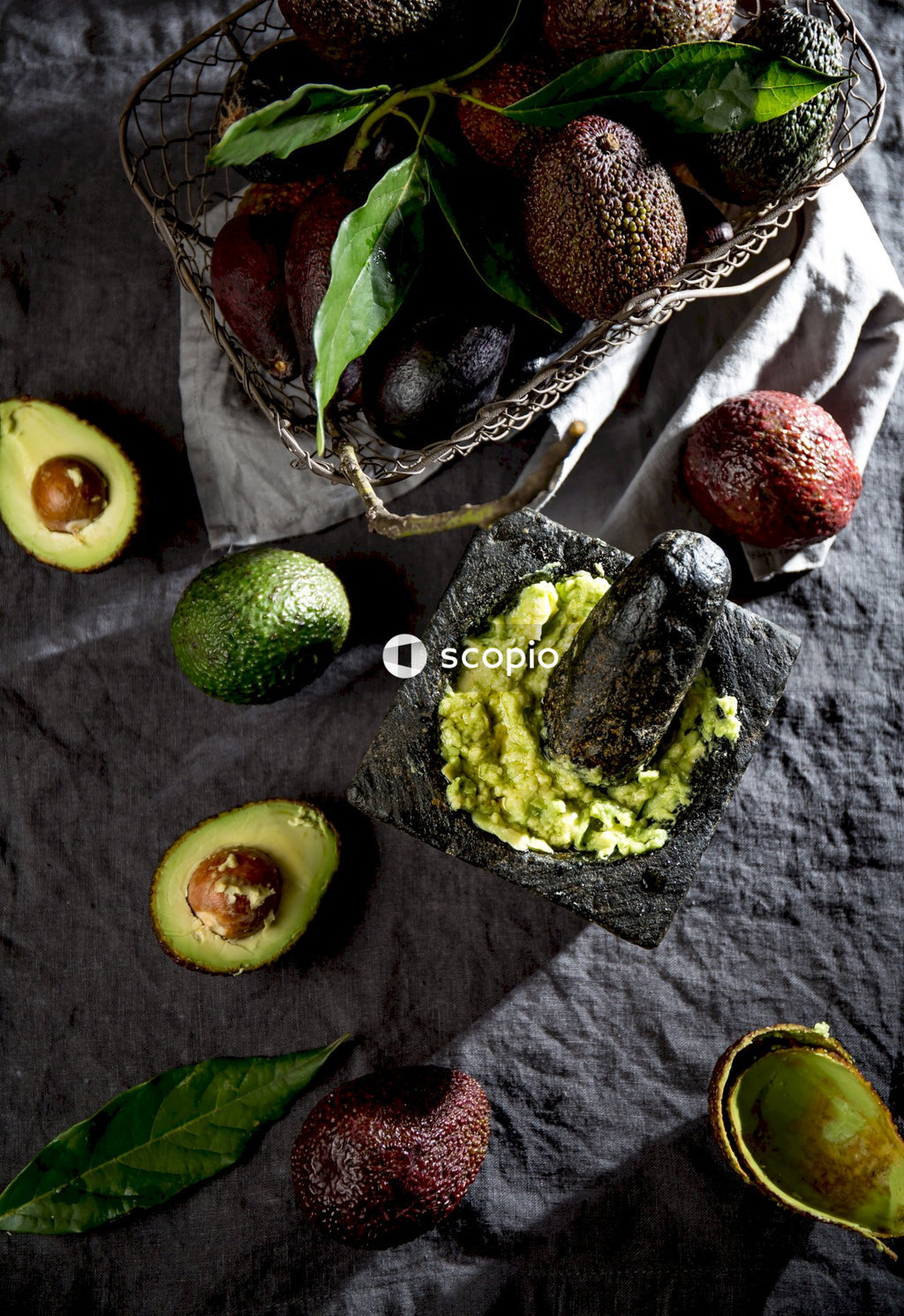 Sliced avocado fruit and red apple fruit on brown woven basket