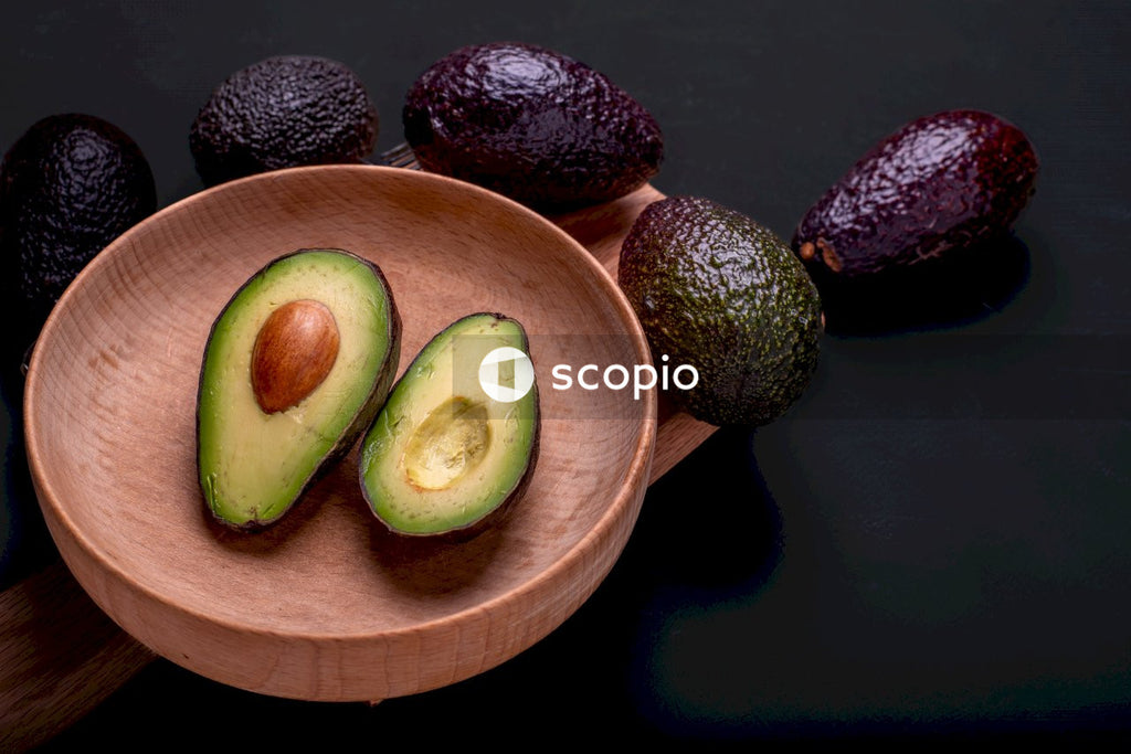 Sliced avocado fruit on brown wooden bowl