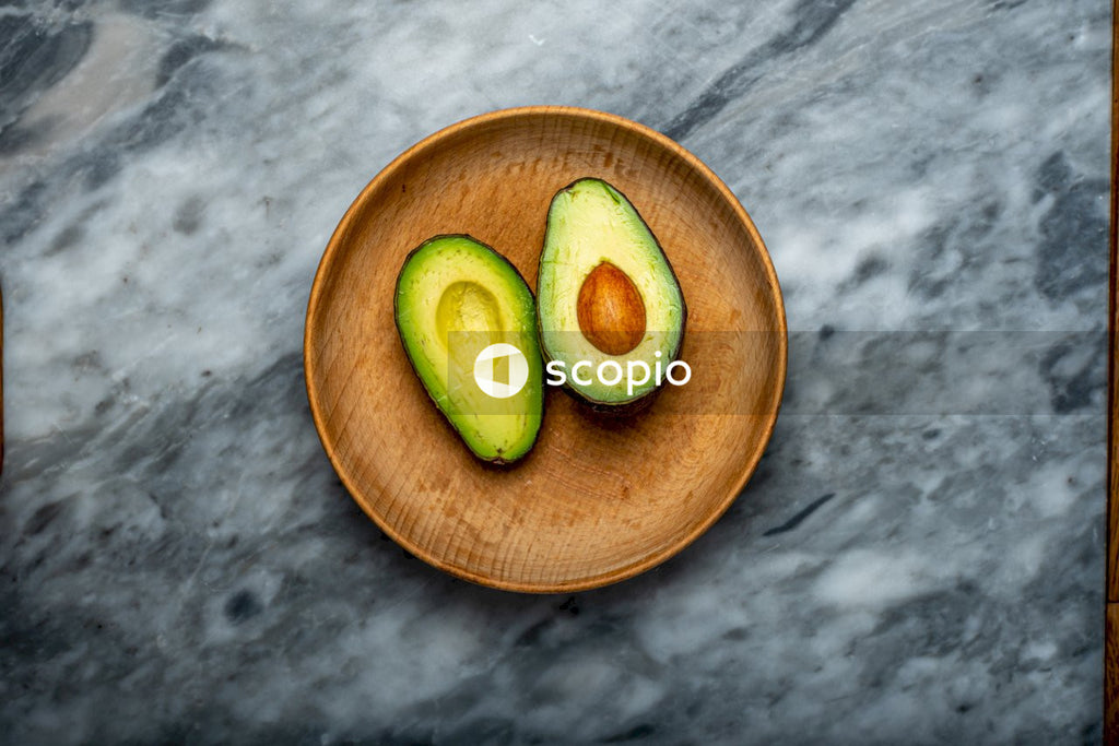 Sliced avocado fruit on brown wooden bowl
