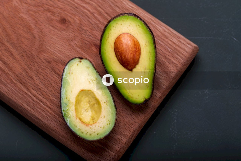 Sliced avocado fruit on brown wooden chopping board