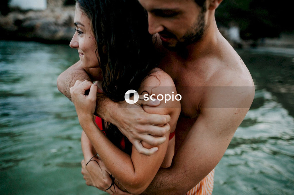 Topless man hugging woman in water