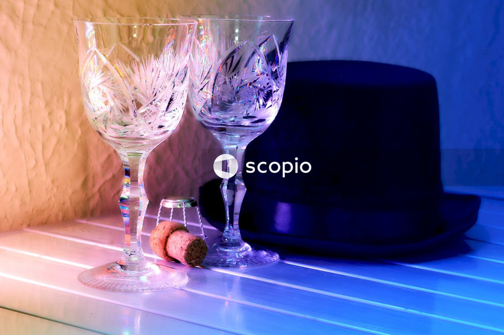 Two crystal wine glasses, a wine cork and a black hat