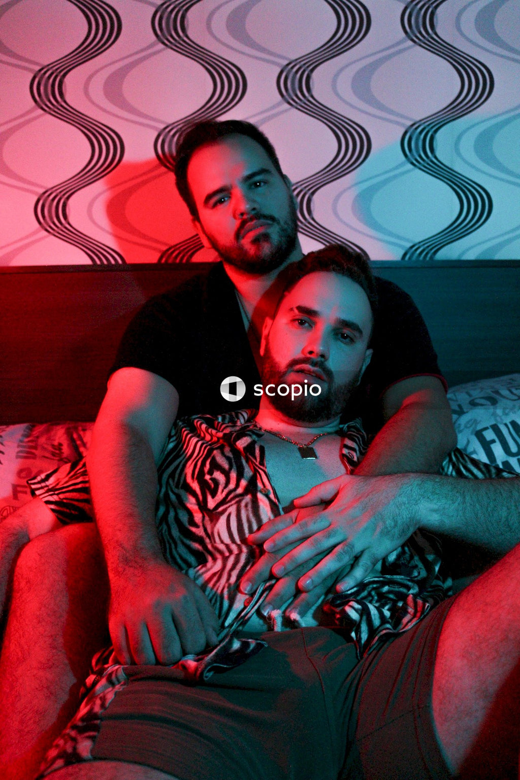 Two men cuddling in red lit bedroom