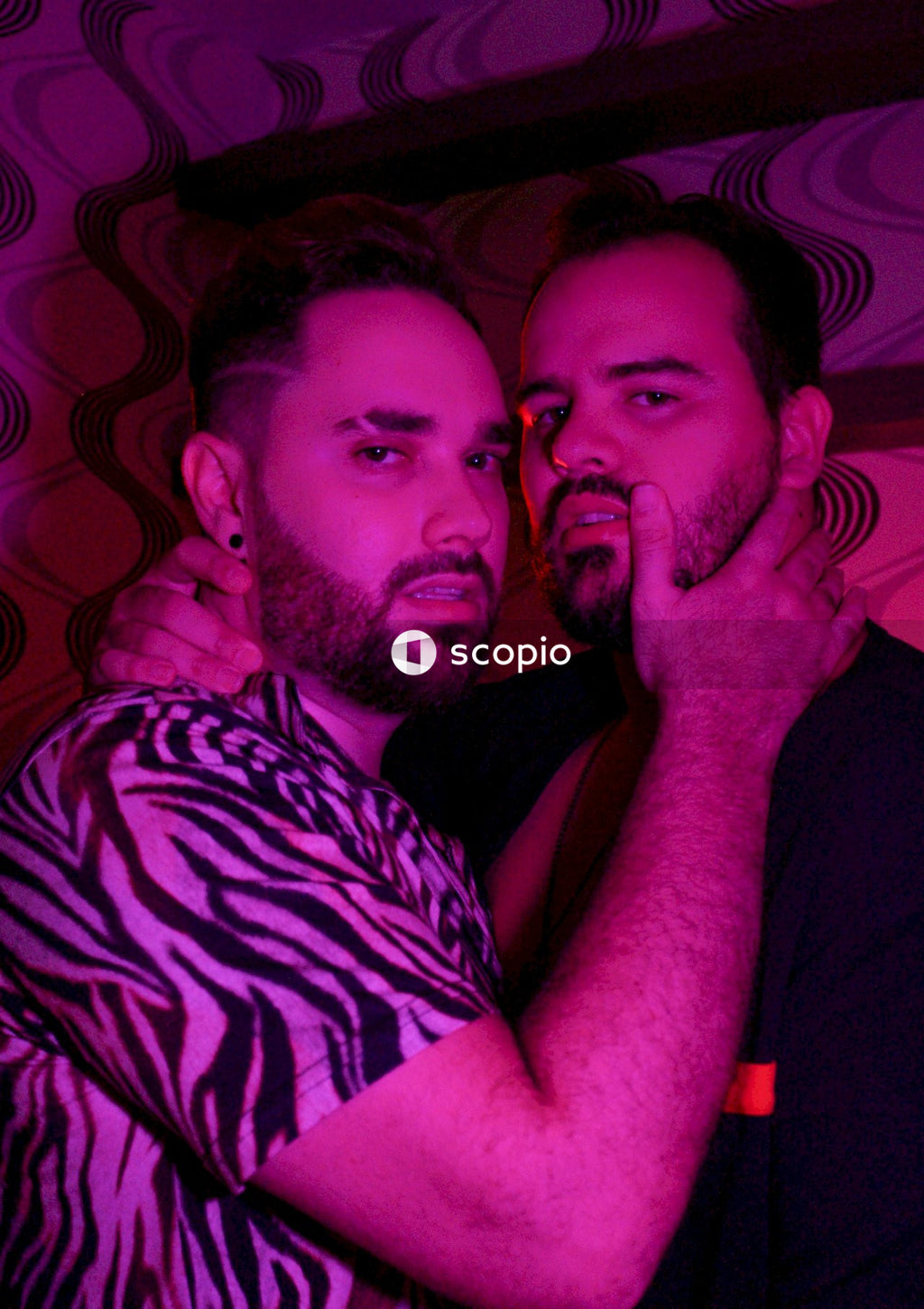 Two men hugging each other in red lit room
