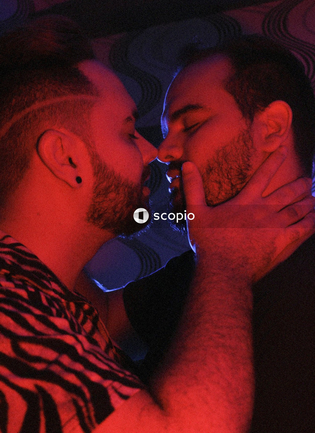 Two men kissing in red lit room