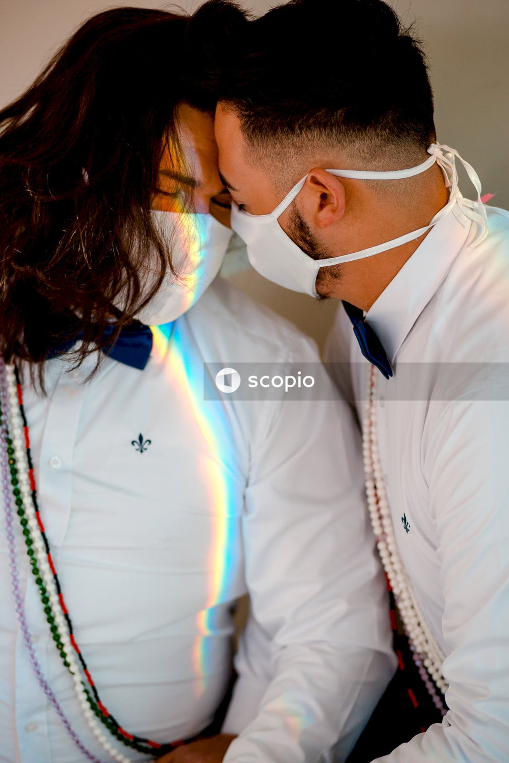 Two newly wedded men with facemasks hugging each other