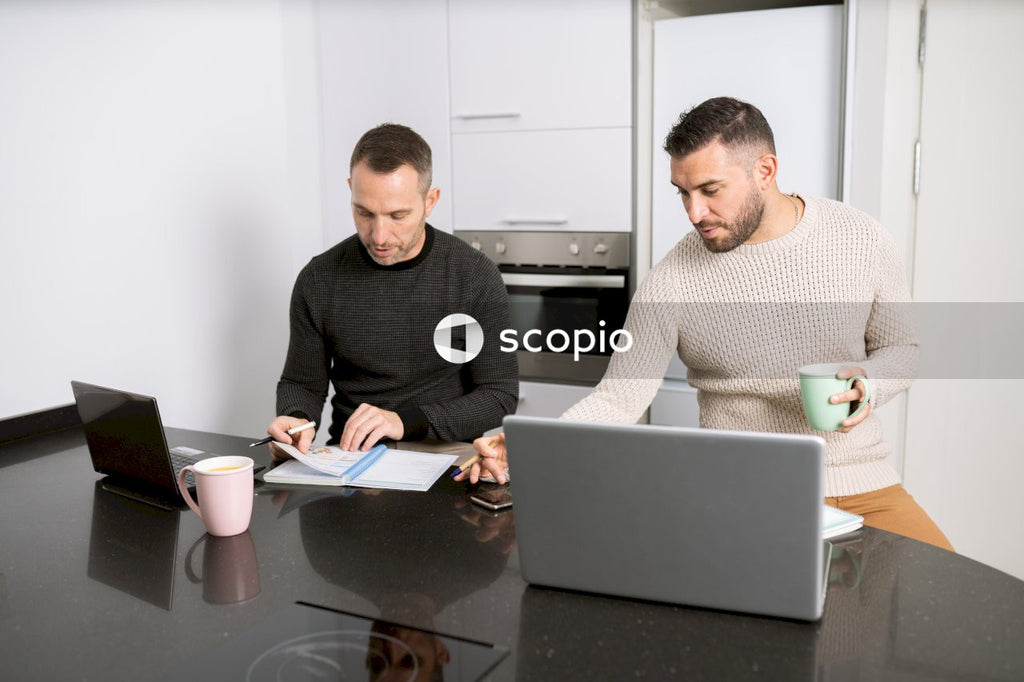 Two men working on their laptops in the kitchen
