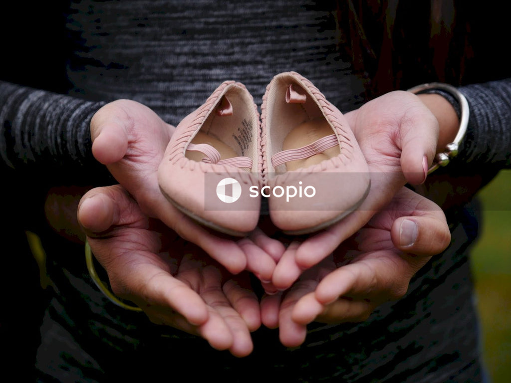 Two people holding pink baby girl shoes in their hands