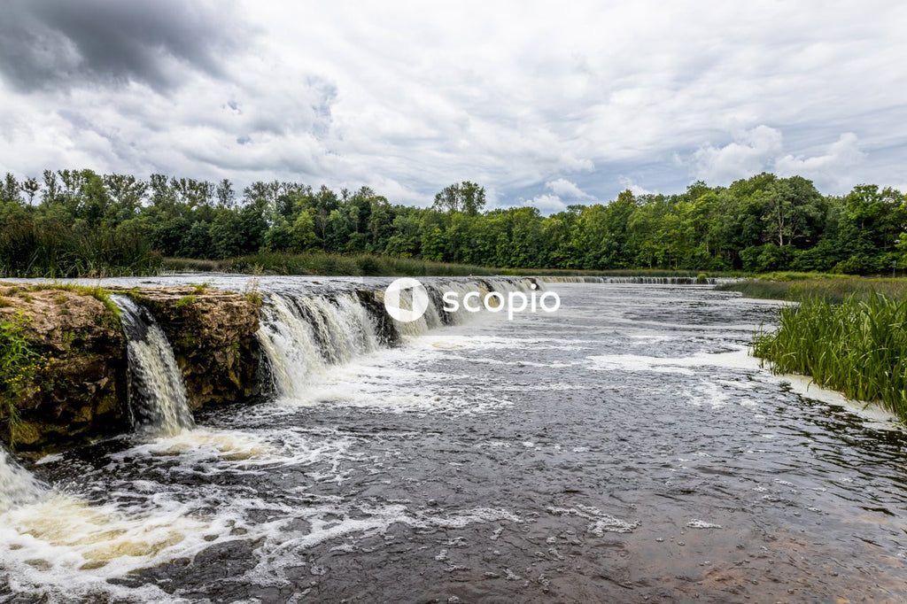 Water falls under cloudy sky