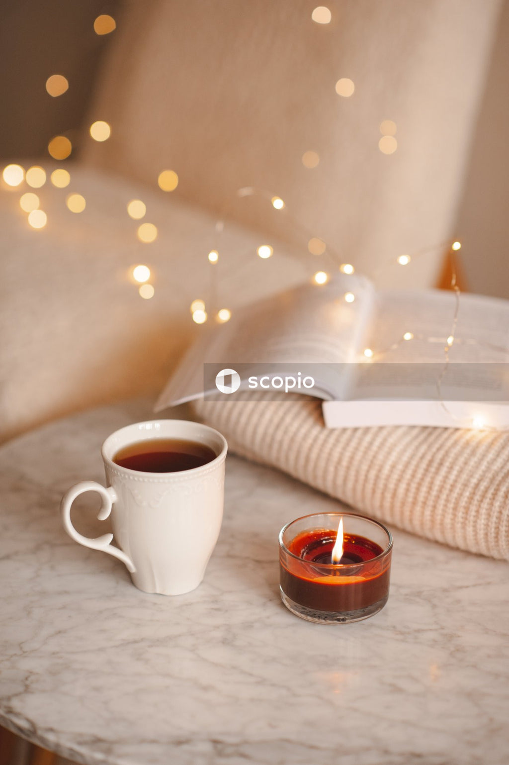 White ceramic mug beside clear glass candle holder on white table
