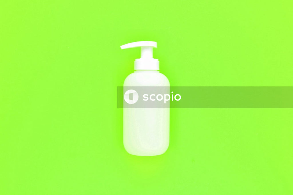 White plastic pump bottle on green surface