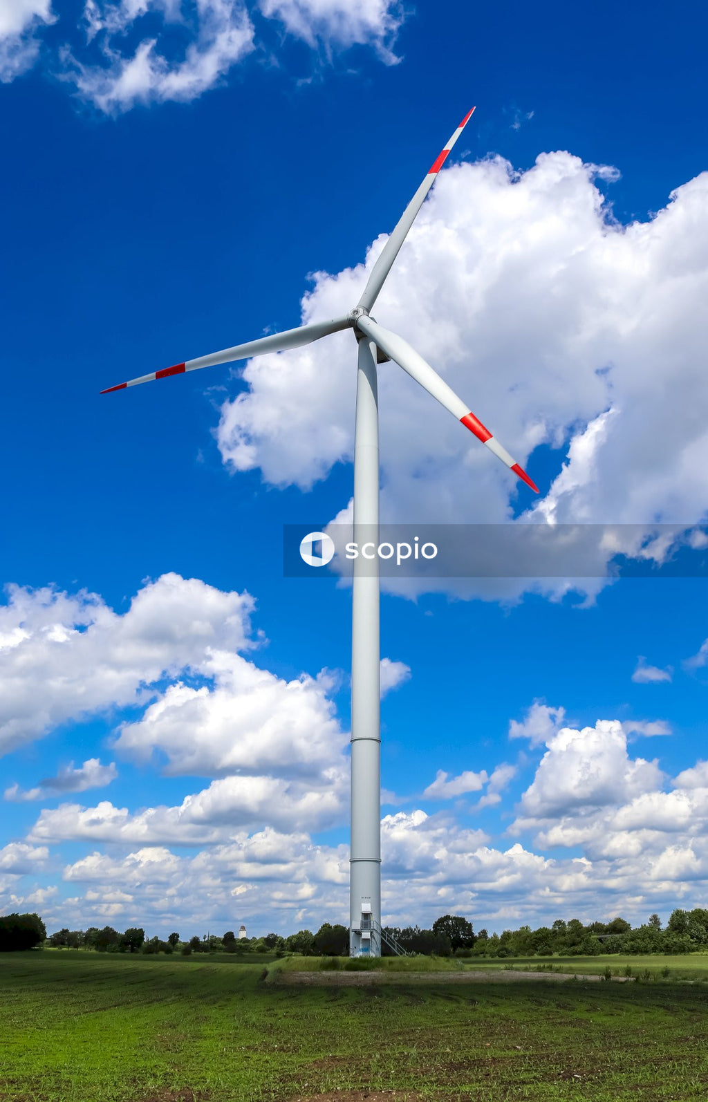 White wind turbine under blue sky and white clouds