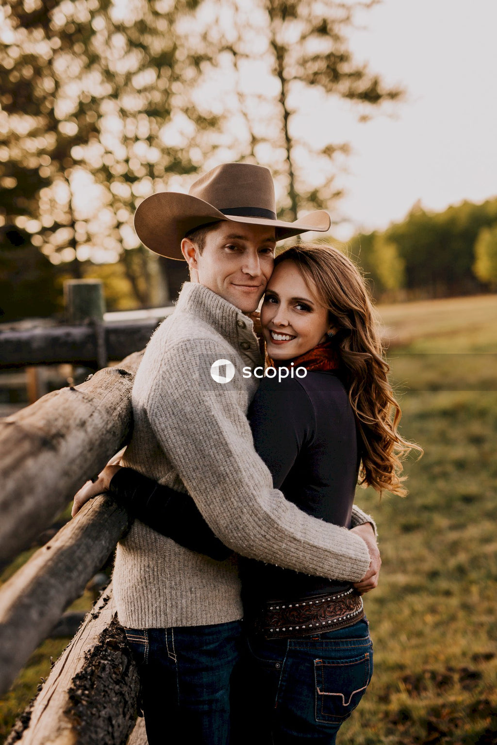 Woman hugging man on brown wooden fence