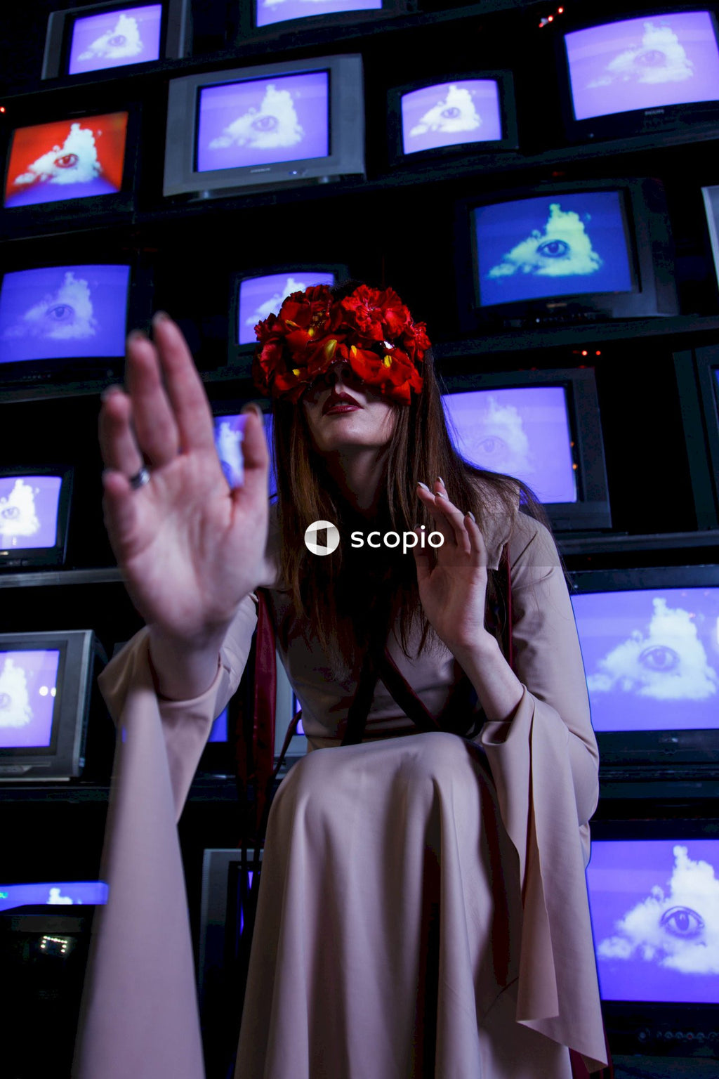 Woman in beige blazer covering her face with orange flower