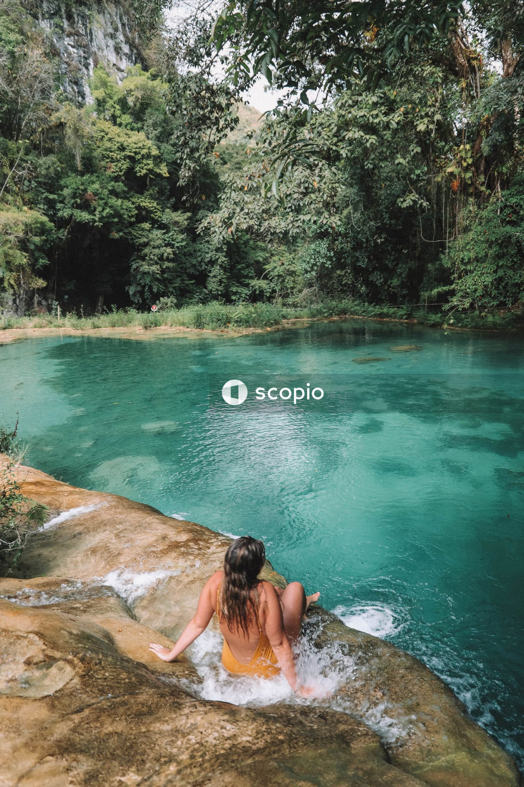 Woman in bikini lying on brown rock in the river