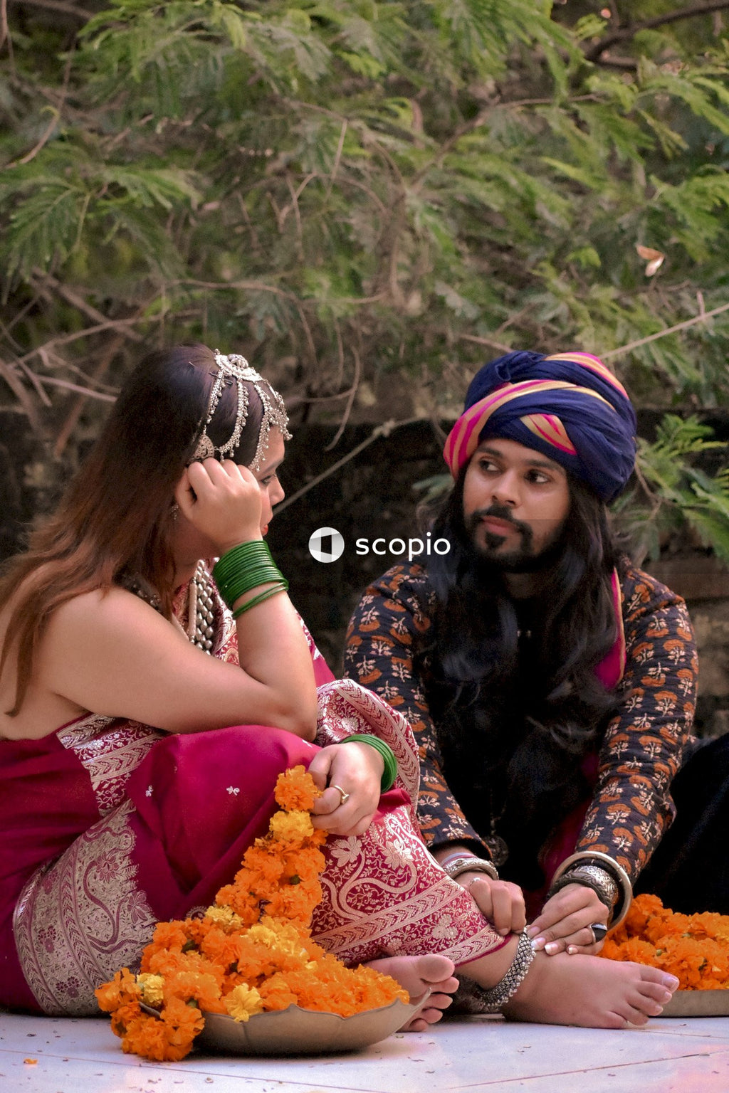 Indian couple in traditional outfit sitting on ground outdoor