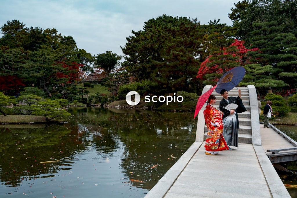 Japanese couple in their traditional outfit standing on concrete pathway in a garden