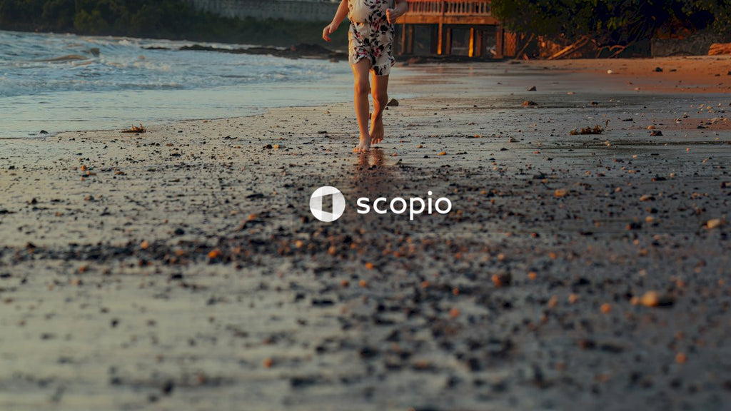 Woman in black and white floral dress walking on beach