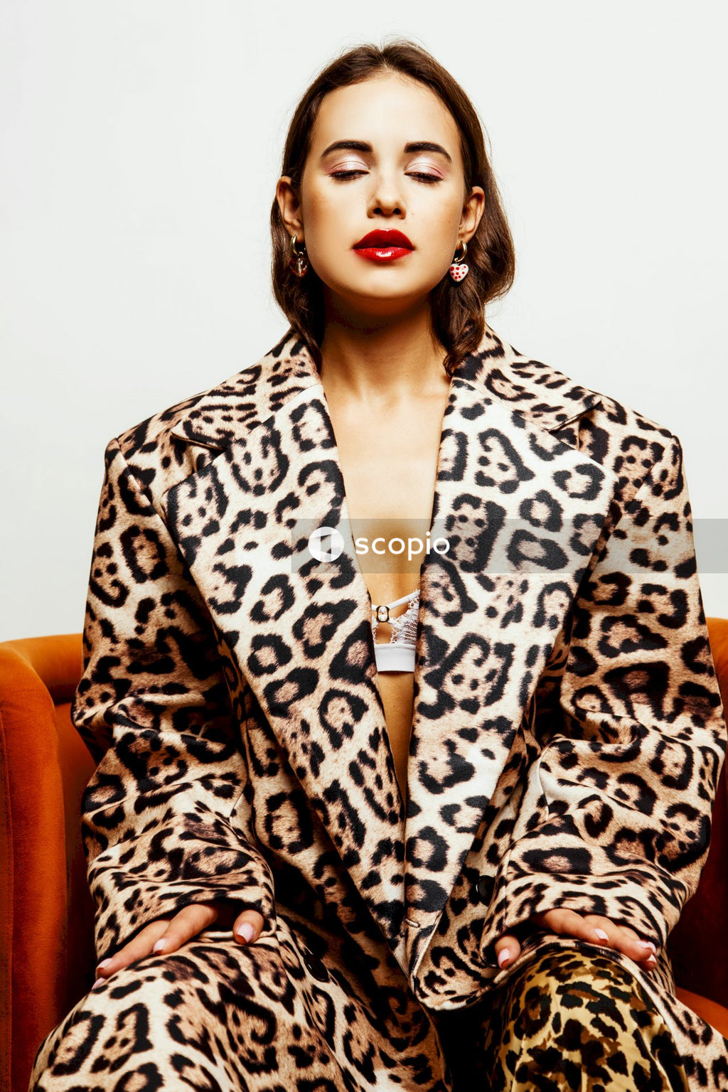 Woman in black and white leopard print robe sitting on orange sofa