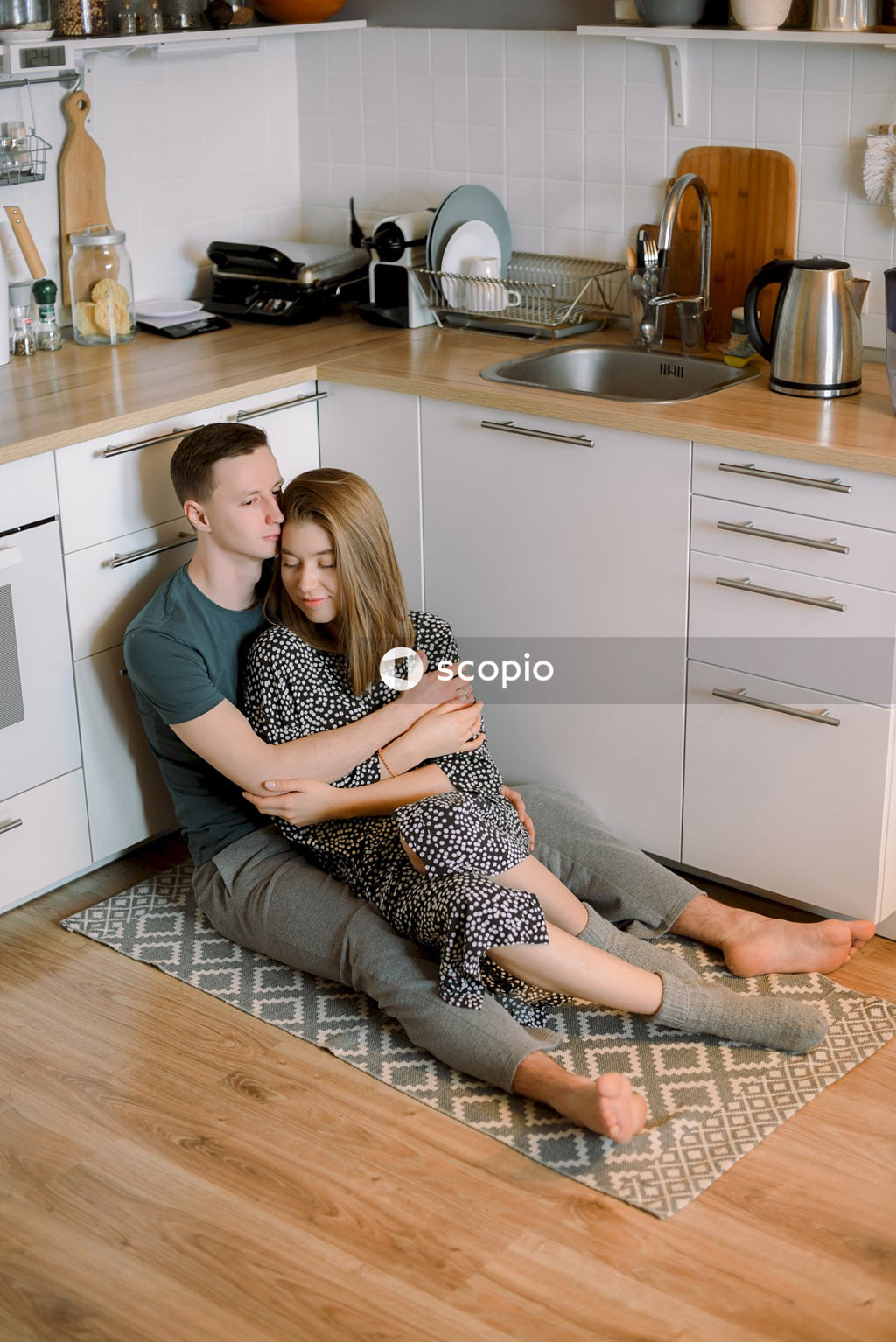 Man and woman hugging and sitting on mat on kitchen floor