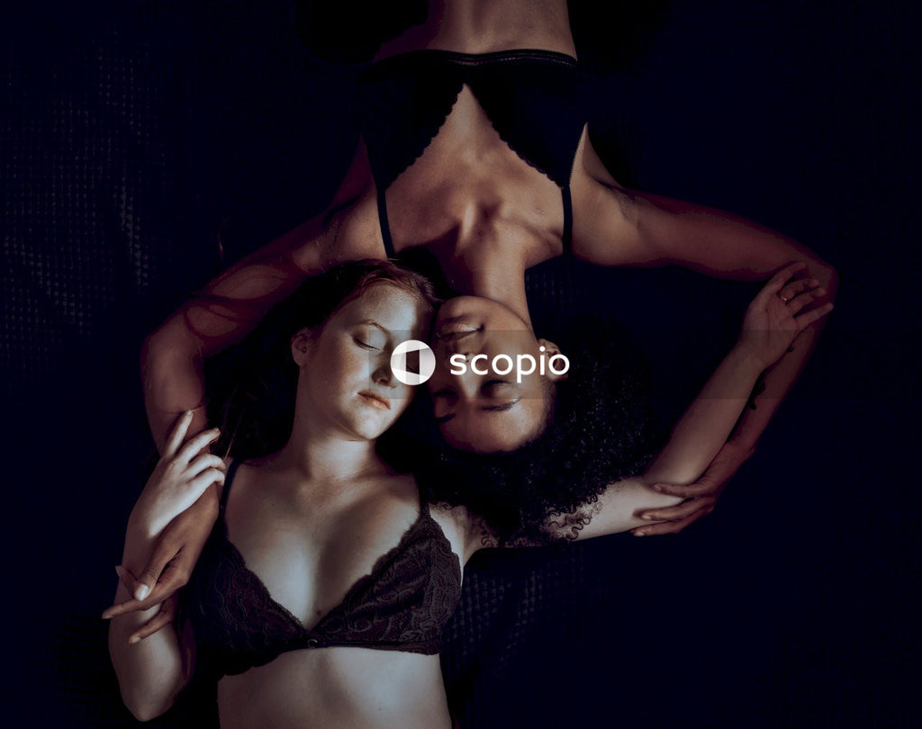 Top view of white woman and Black woman in bra laying beside each other