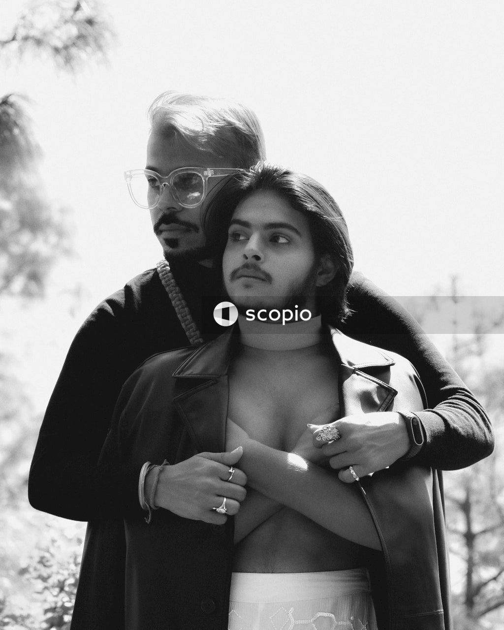 Grayscale photo of man hugging his partner from the back looking away