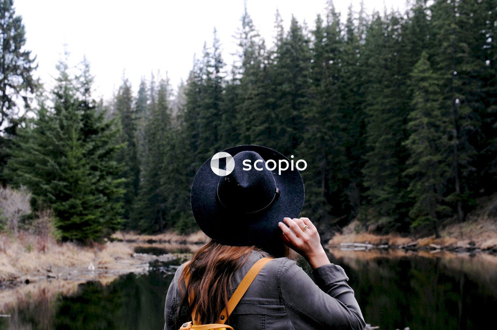 Woman in black hat and black jacket standing near lake