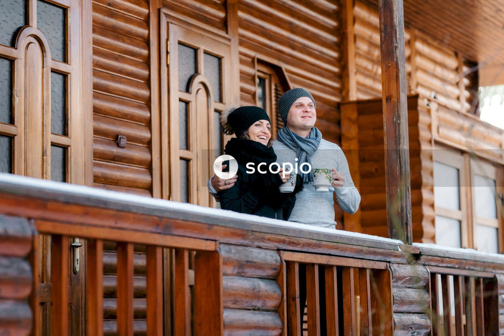 Woman and man drinking hot drink and standing on balcony
