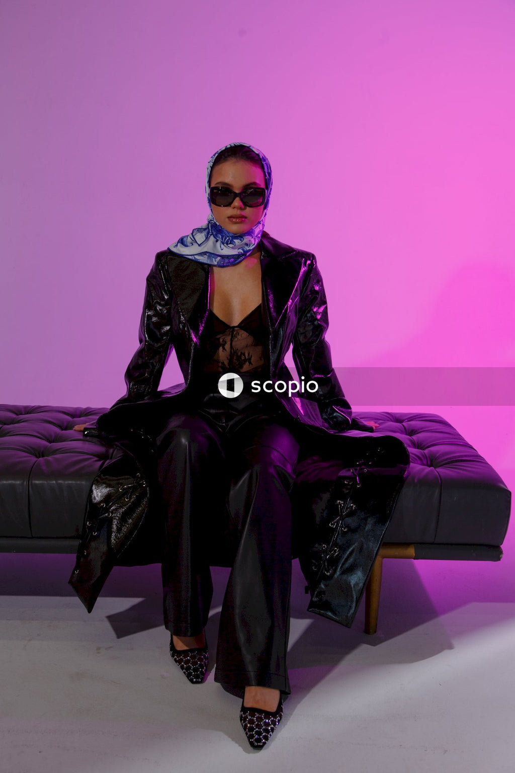 Woman in black leather jacket and black pants sitting on purple couch