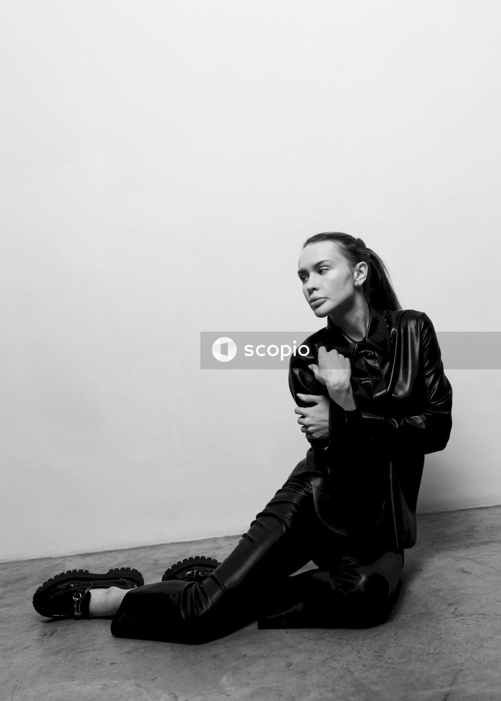 Woman in black leather jacket and black pants sitting on rock
