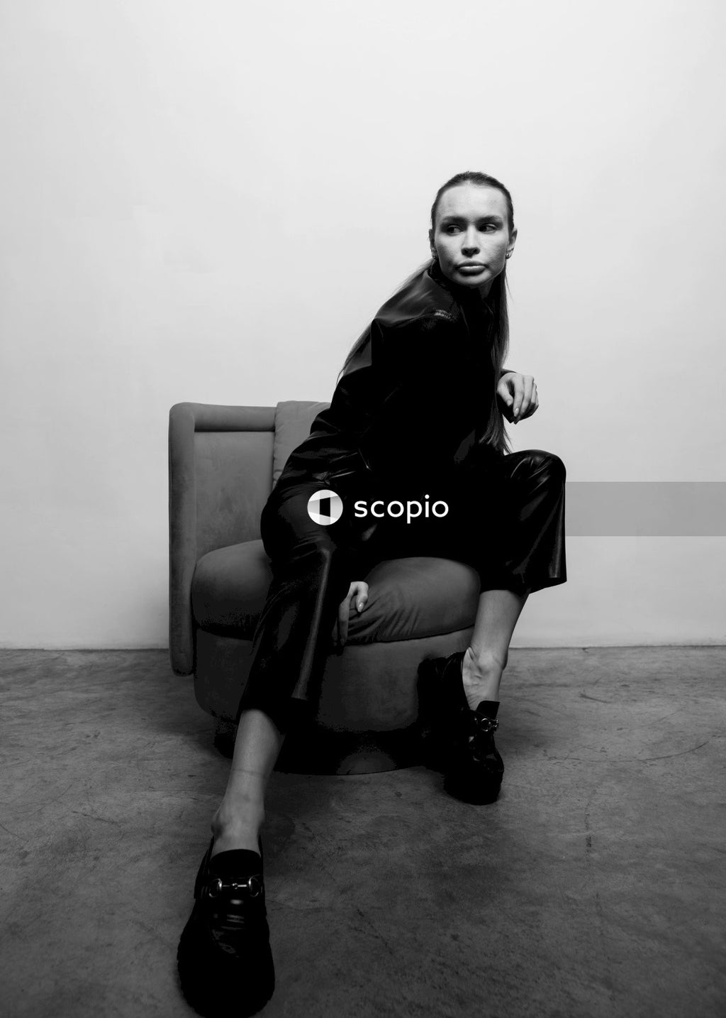 Woman in black leather jacket sitting on black leather armchair