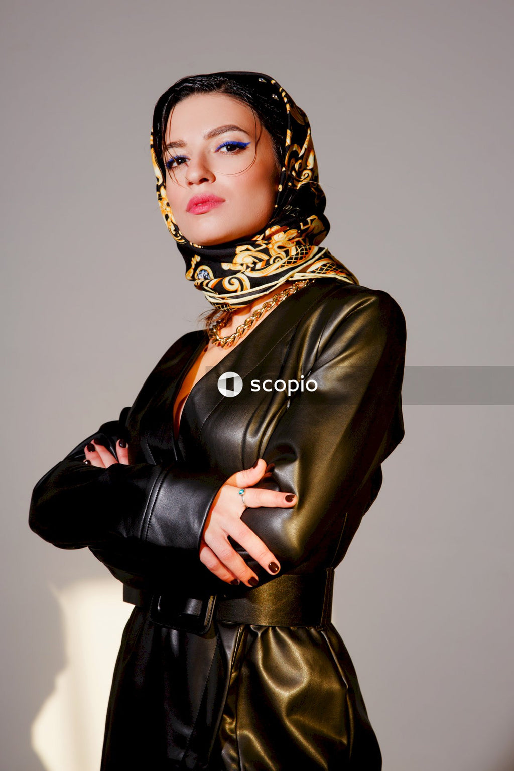 Woman in black leather jacket wearing gold hijab