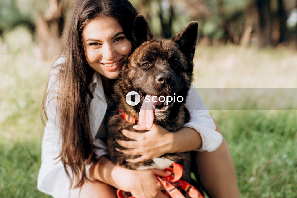 Woman in black tank top hugging brown and black short coated dog