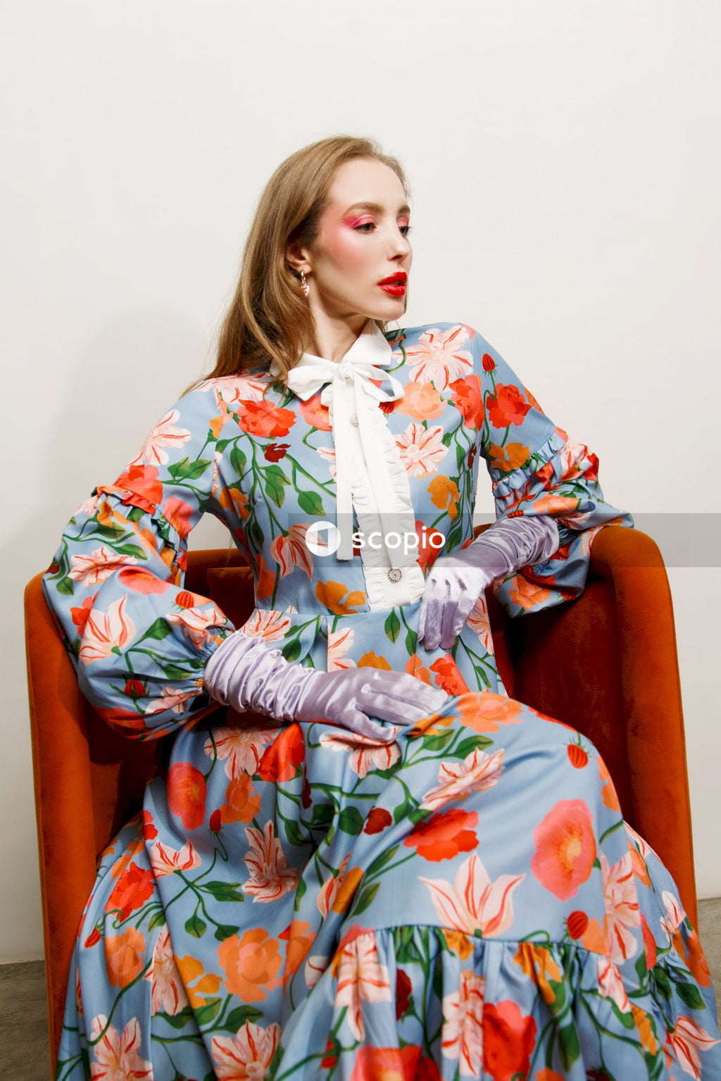 Woman in blue and white floral dress sitting on brown sofa