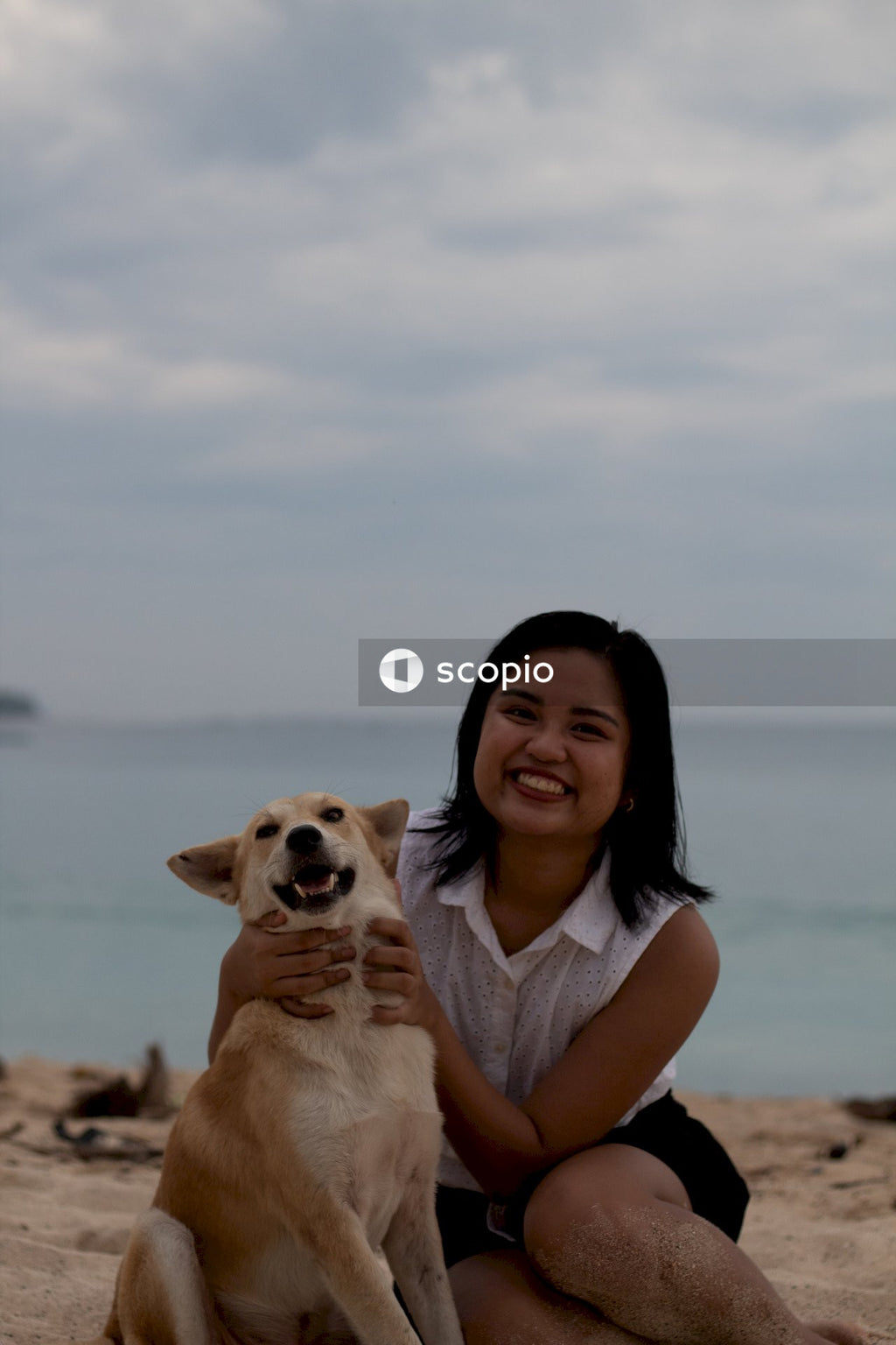 Woman in blue tank top hugging brown short coated dog