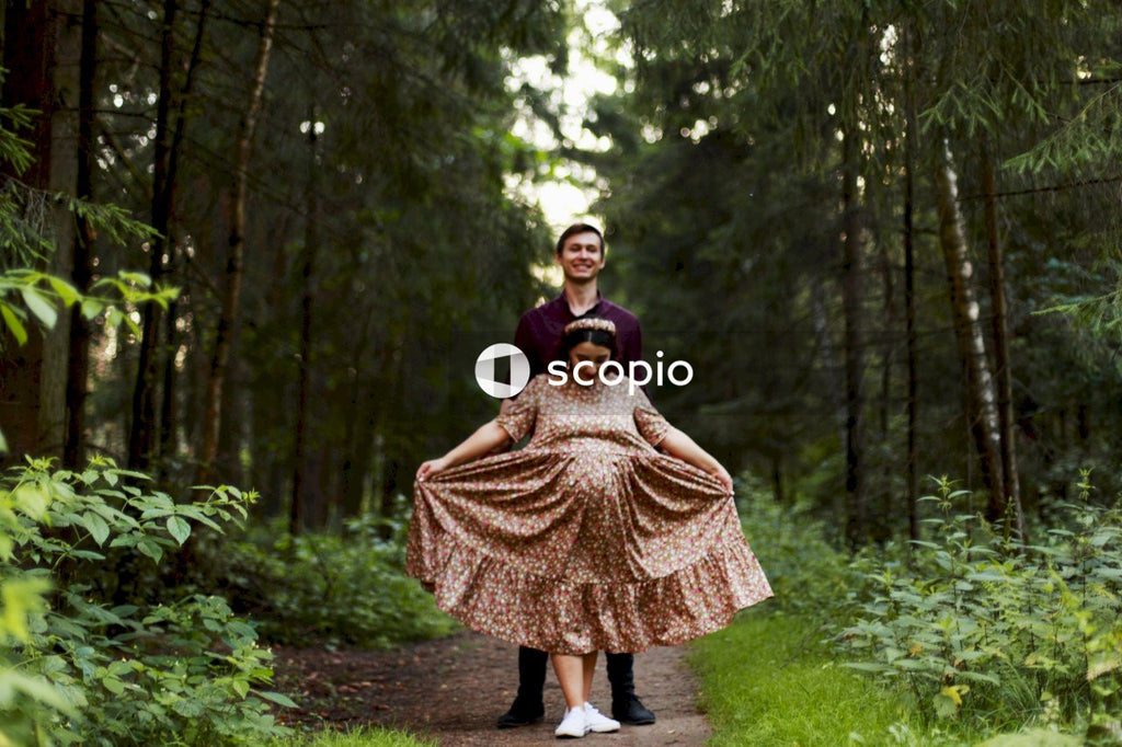 Woman in brown and beige dress standing on forest