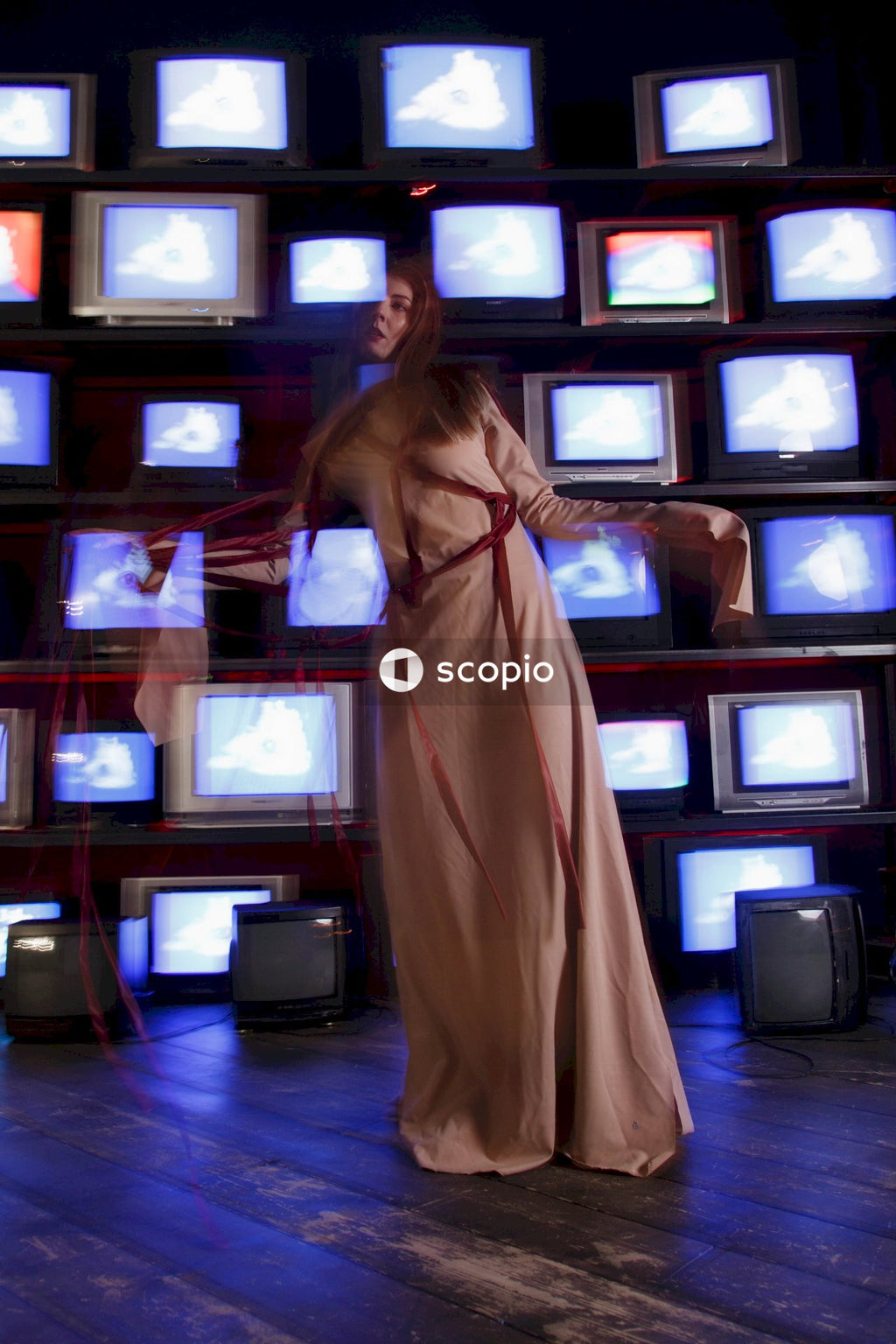 Woman in brown dress standing in front of black crt tv
