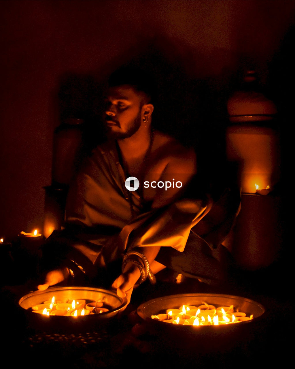 Woman in brown robe sitting beside lighted candles
