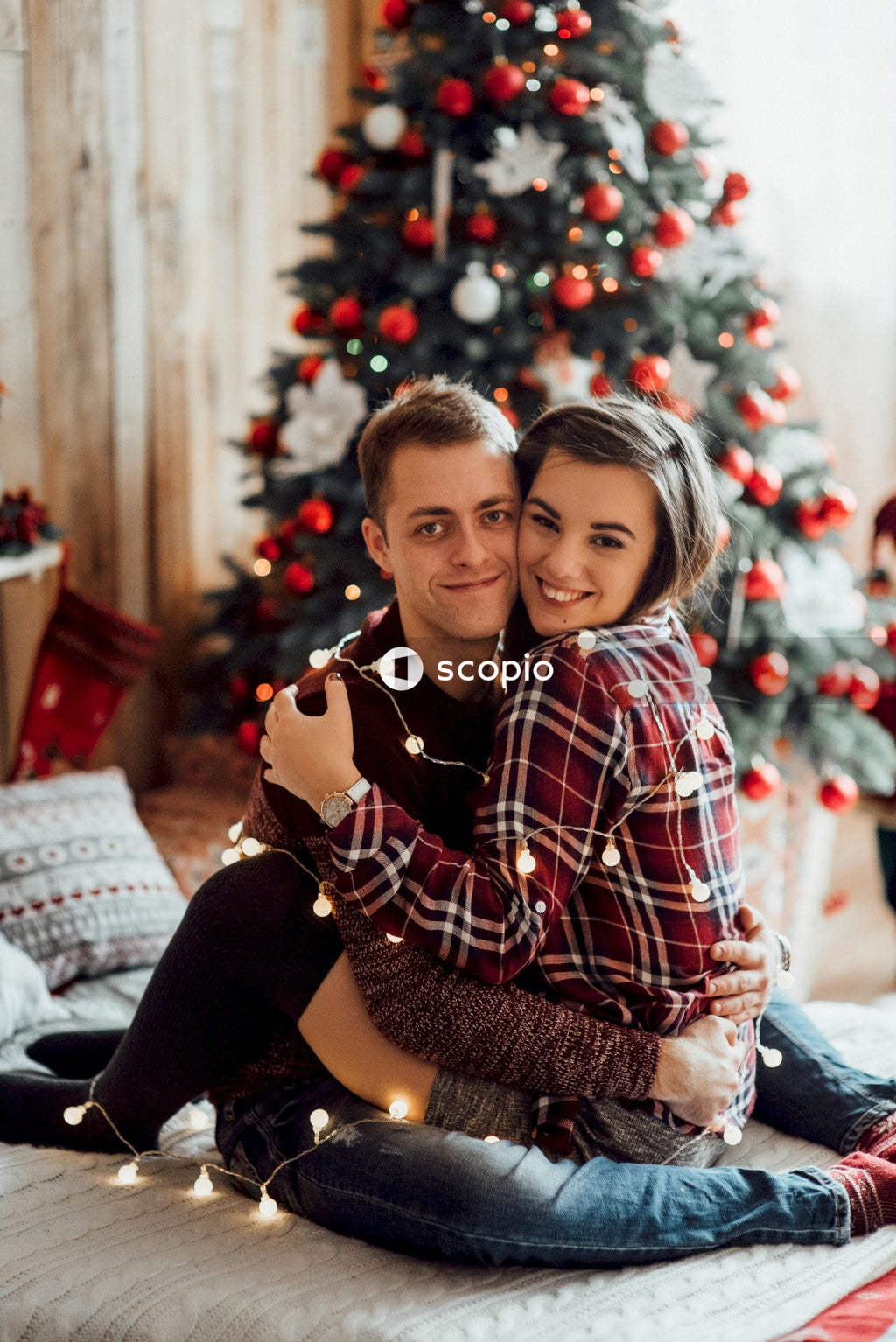 Man and woman hugging in living room beside Christmas tree
