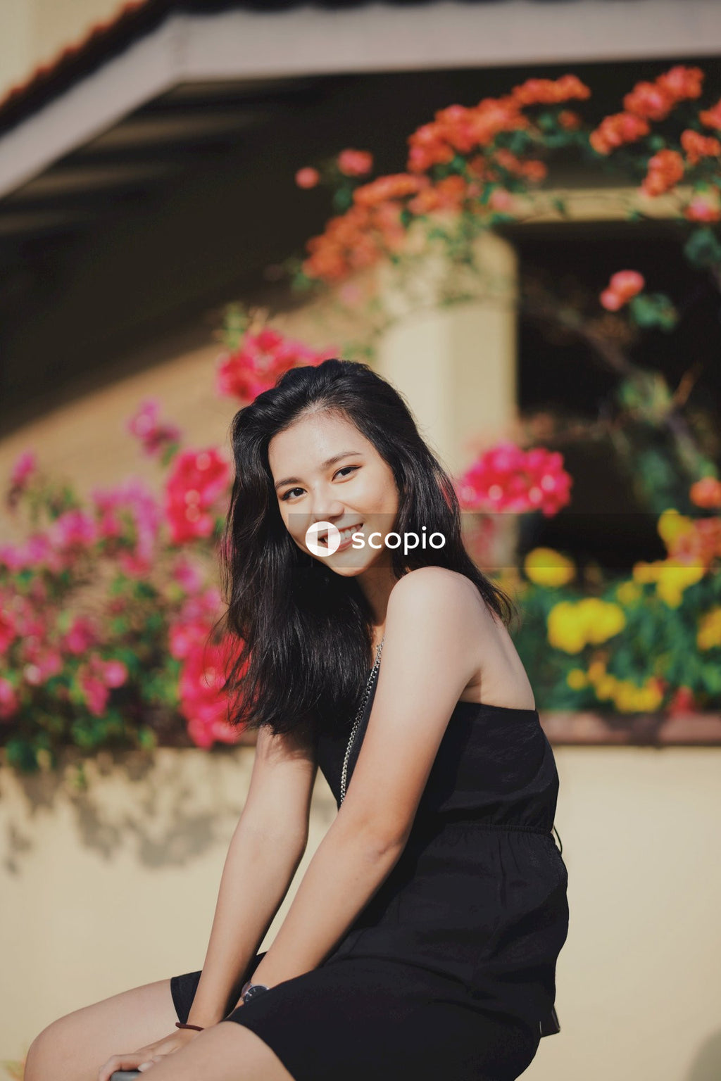 Woman in dark dress posing near flowers bushes