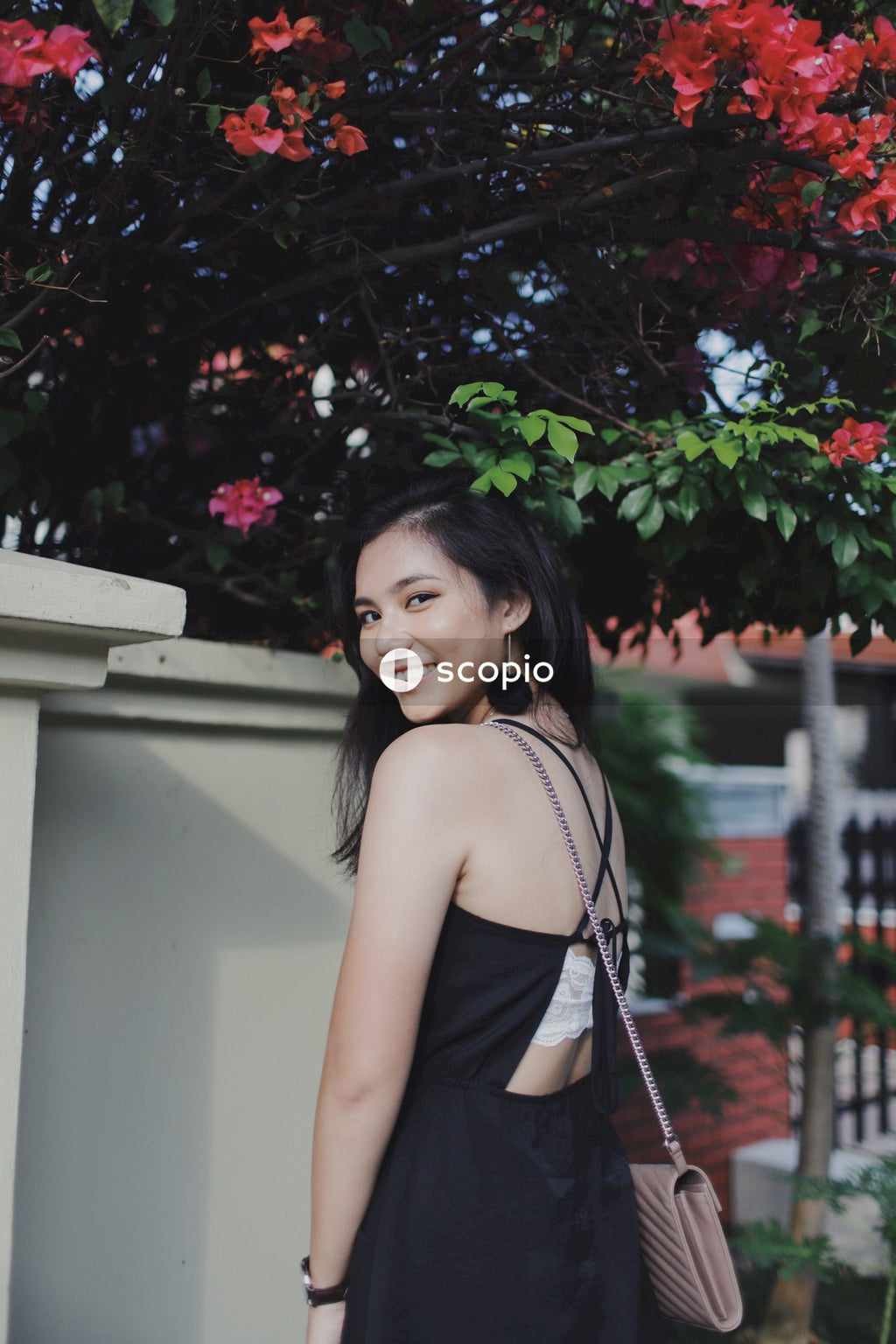 Woman in dark dress posing near flowers bushes