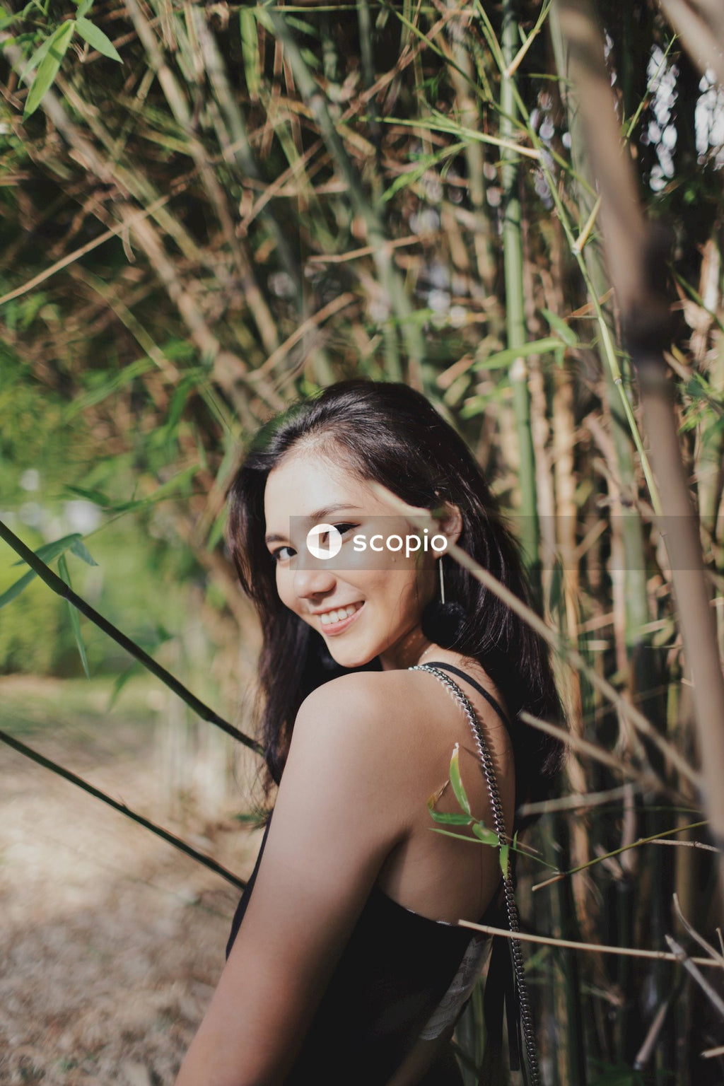 Woman in dark dress posing near flowers bushes