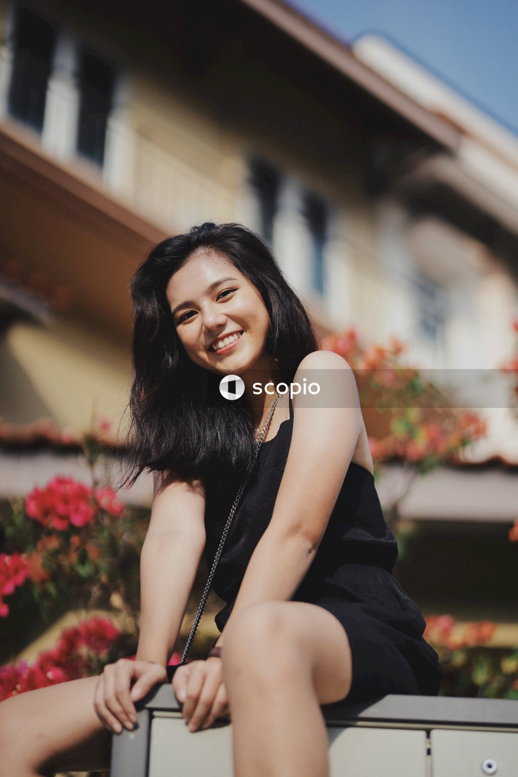 Woman in dark dress posing near flowers bushes