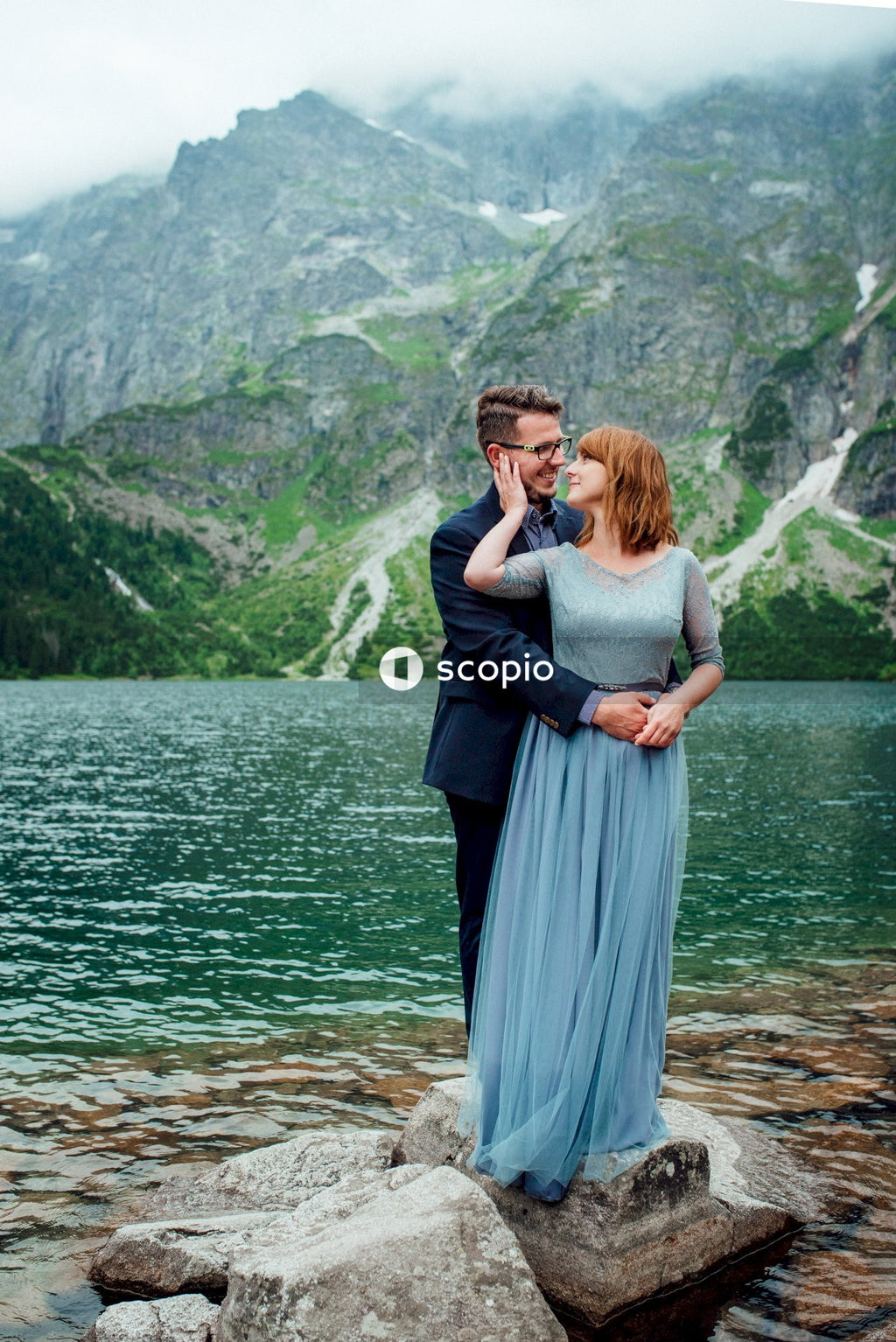 Woman in gray dress hugging woman in gray dress near body of water