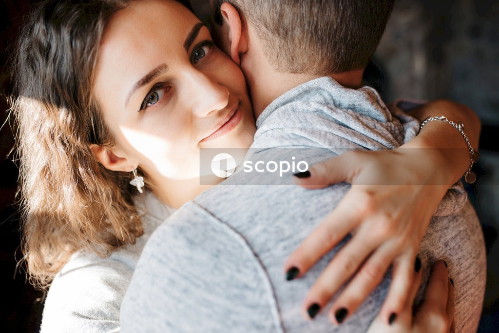 Woman in gray shirt hugging man in gray shirt