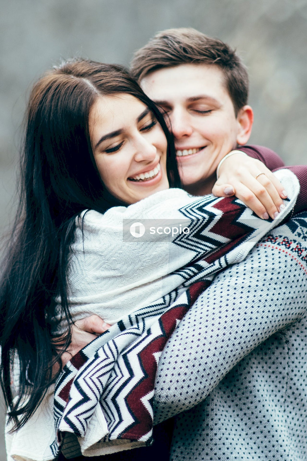 Woman in gray sweater hugging boy in red and white shirt