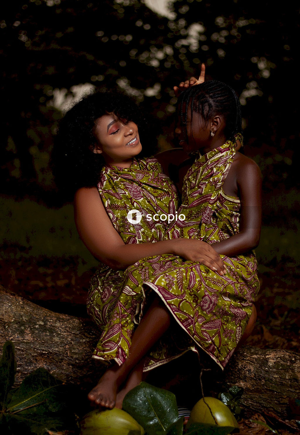 Woman in green and brown floral dress hugging woman in green and brown dress