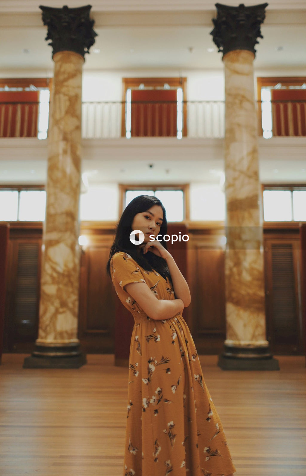 Woman in long orange dress standing in big hall