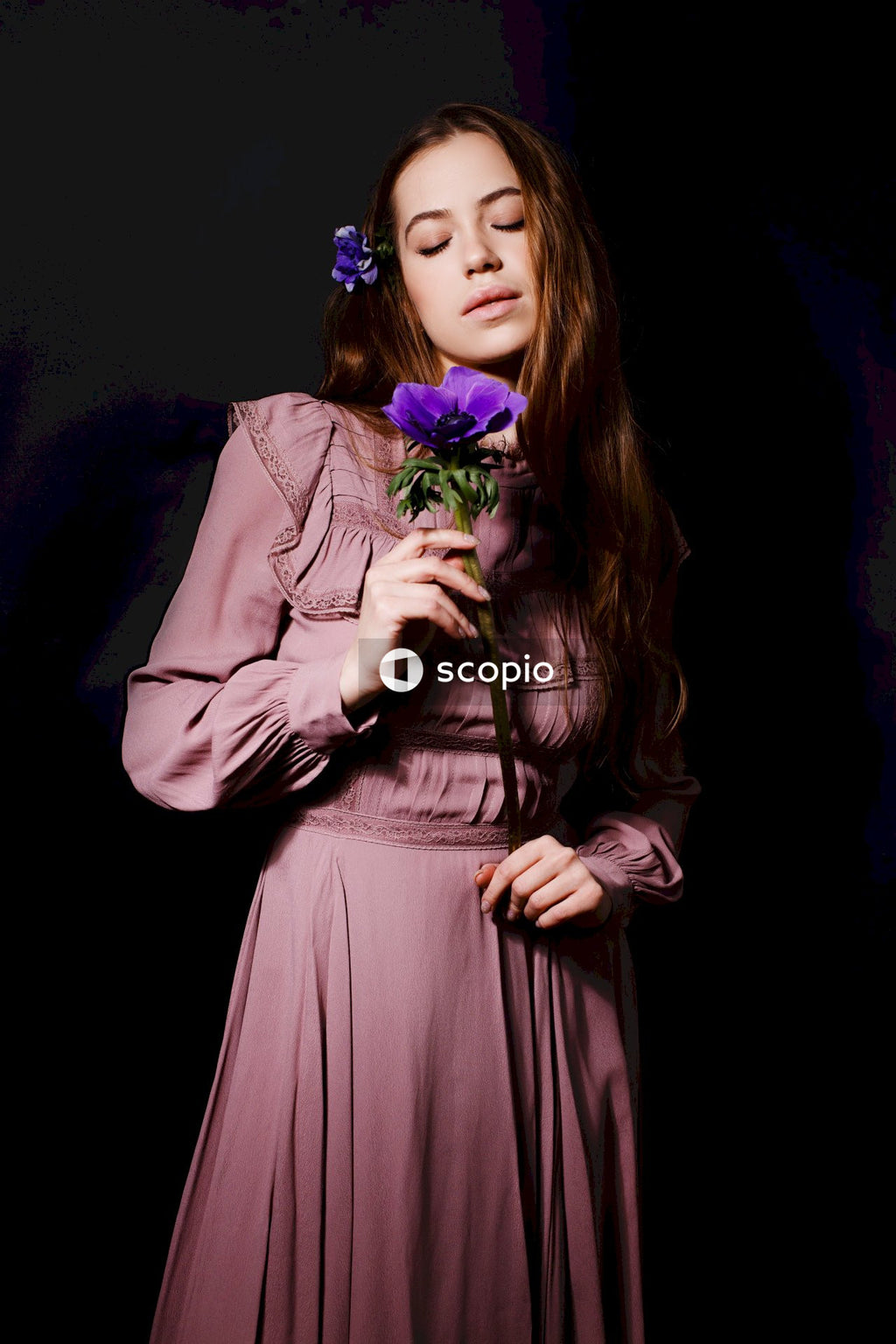 Woman in pink long sleeve dress holding purple flower