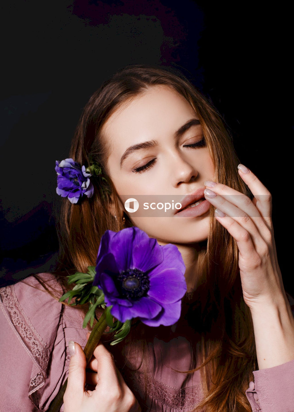 Woman in pink long sleeve shirt with purple flower on ear
